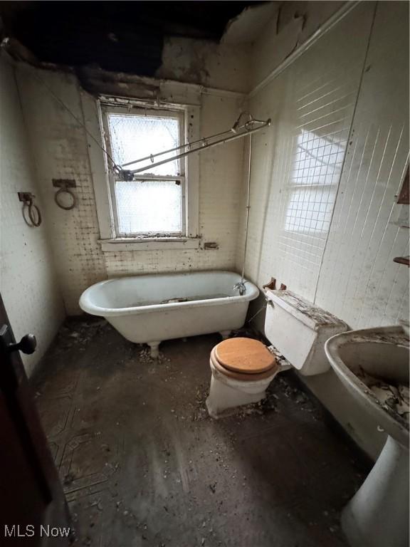 bathroom with a washtub and toilet