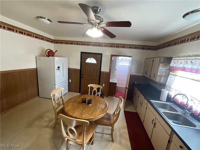 dining area featuring sink, ceiling fan, and wood walls