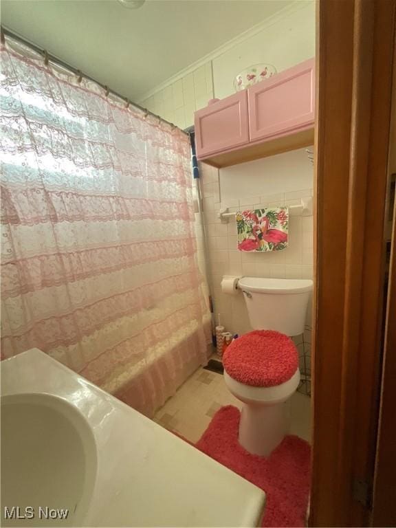 bathroom featuring tile walls and toilet