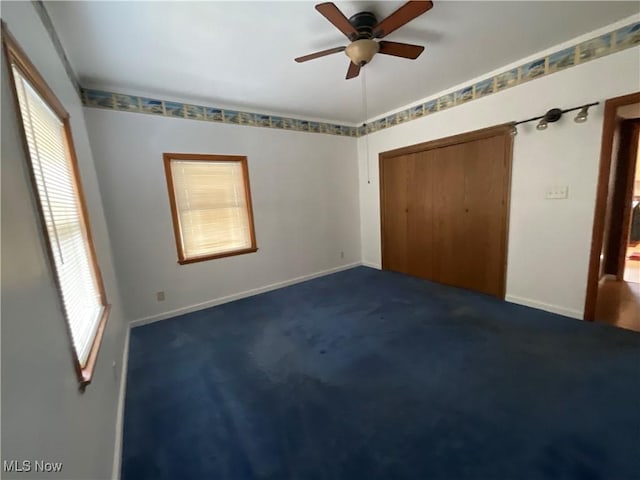 unfurnished bedroom with dark carpet, a closet, and ceiling fan