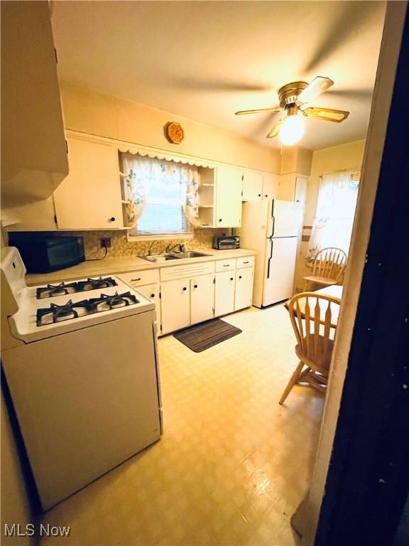 kitchen featuring white cabinetry, sink, white appliances, and ceiling fan