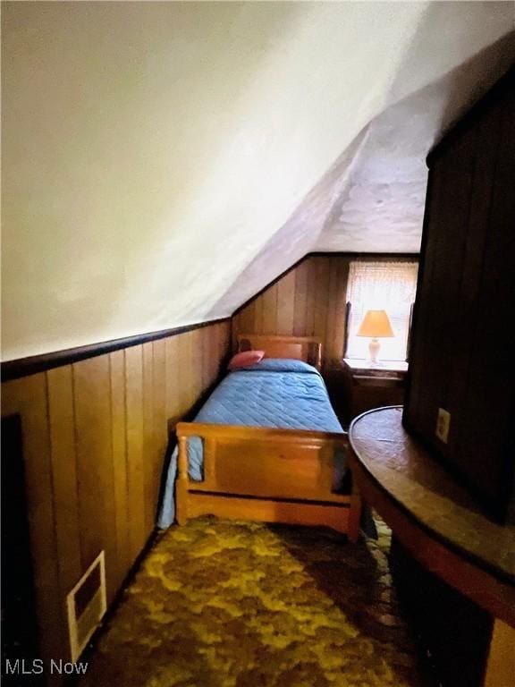 bedroom with vaulted ceiling and wood walls