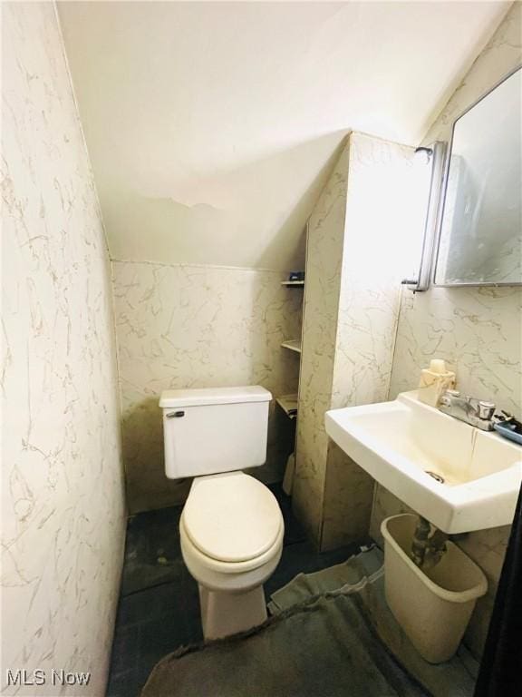 bathroom with sink, toilet, and vaulted ceiling