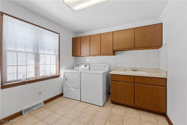 laundry room featuring light tile patterned flooring, cabinets, sink, and washer and dryer