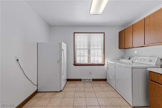 clothes washing area with light tile patterned floors, cabinets, and washing machine and clothes dryer