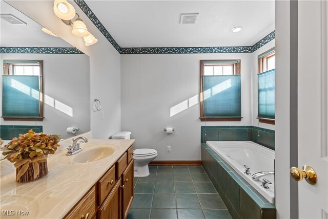 bathroom featuring vanity, a healthy amount of sunlight, tiled bath, and tile patterned floors