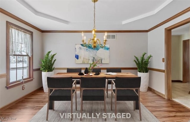 dining room featuring visible vents, wood finished floors, a tray ceiling, and a chandelier