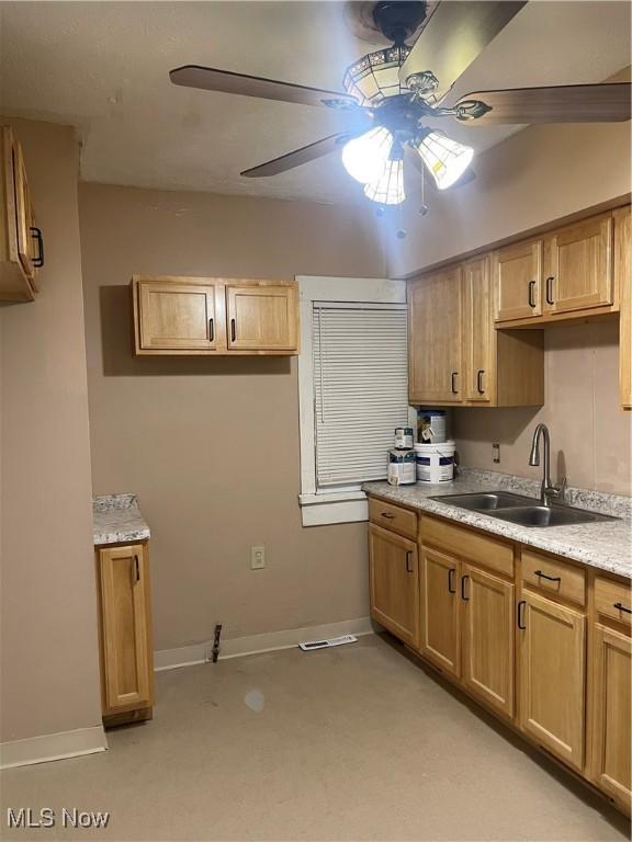 kitchen with light stone countertops, sink, and ceiling fan