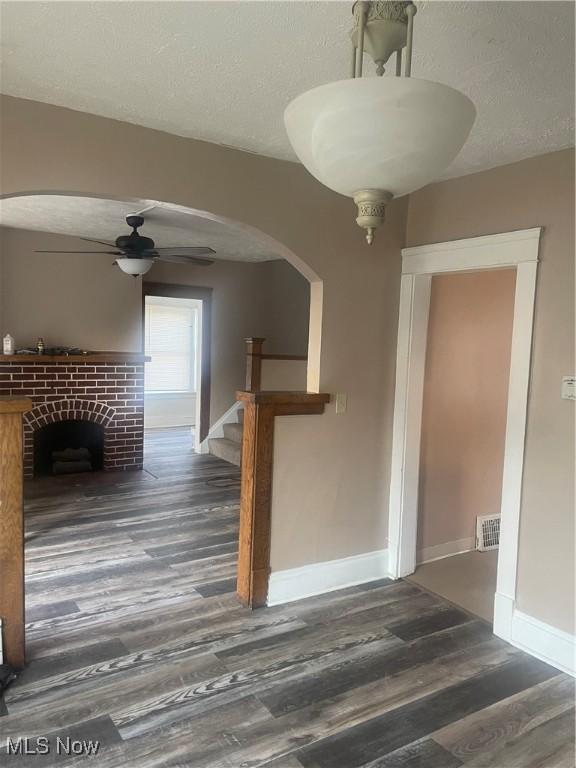 unfurnished living room with dark hardwood / wood-style flooring, a textured ceiling, and ceiling fan