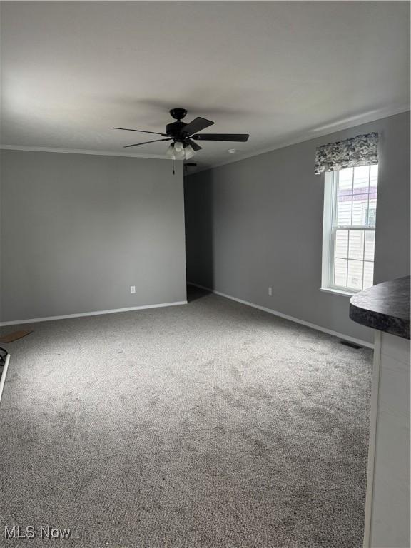 carpeted spare room featuring crown molding and ceiling fan