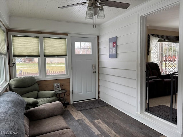 entrance foyer with ceiling fan, wooden walls, a wealth of natural light, and dark hardwood / wood-style flooring