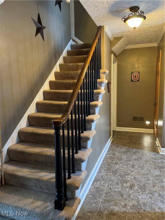 stairway with ornamental molding and a textured ceiling