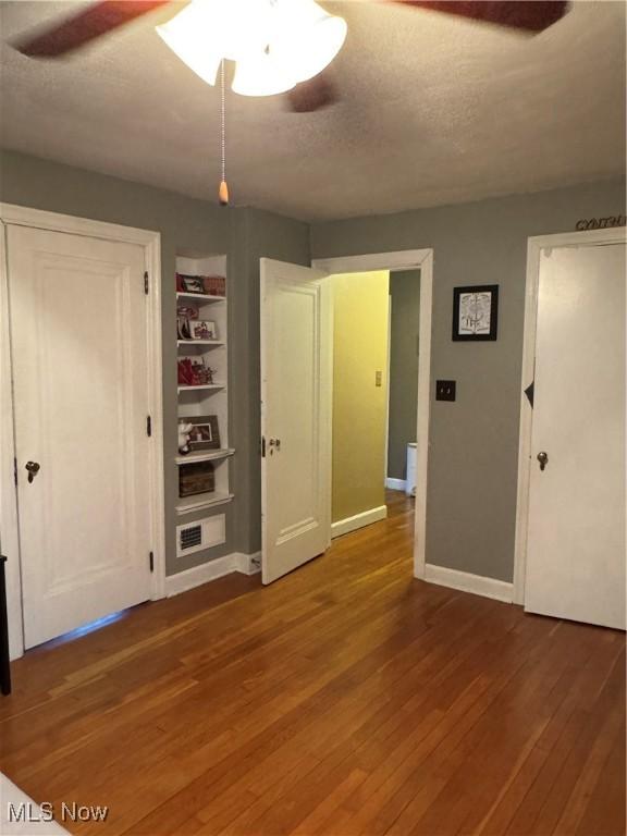 unfurnished bedroom featuring ceiling fan, hardwood / wood-style flooring, and a textured ceiling