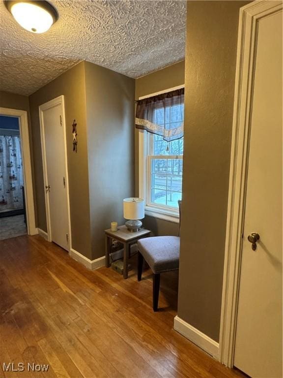 hall with hardwood / wood-style floors and a textured ceiling