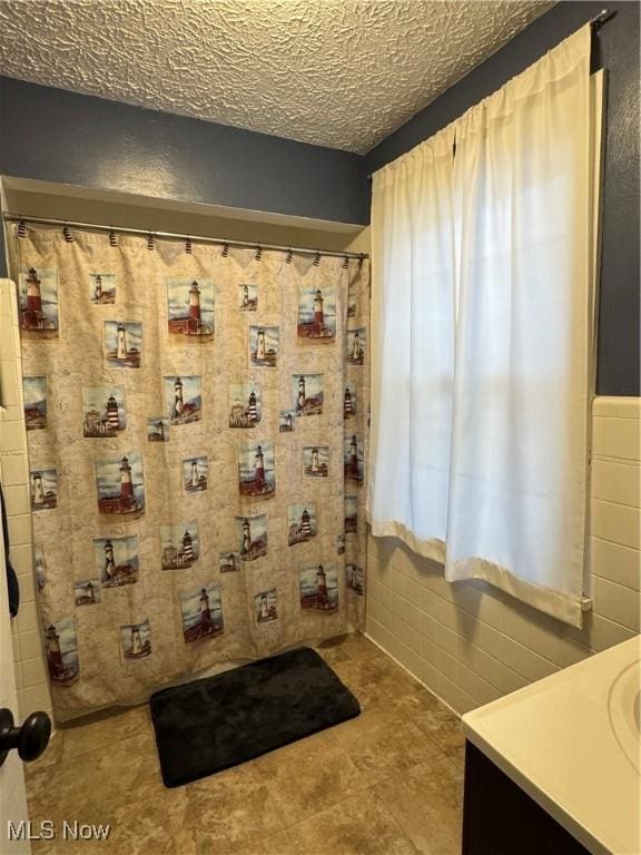 bathroom with vanity, tile walls, and a textured ceiling