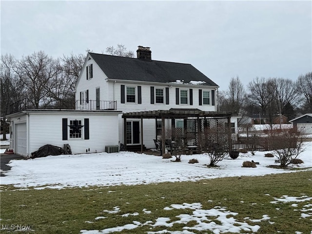 snow covered back of property featuring a garage and a lawn