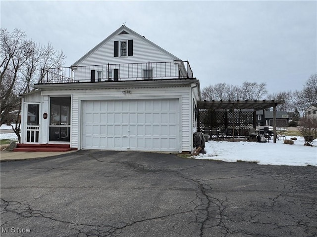 view of snow covered exterior featuring a garage, a pergola, and a balcony