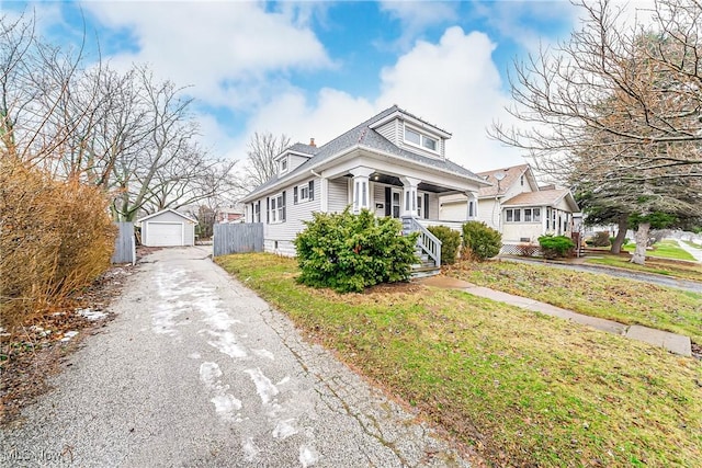 bungalow with a garage, an outdoor structure, a front yard, and a porch