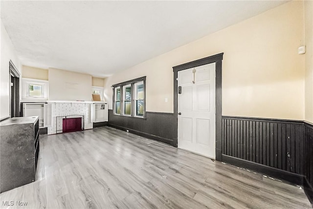 unfurnished living room featuring a brick fireplace and light wood-type flooring