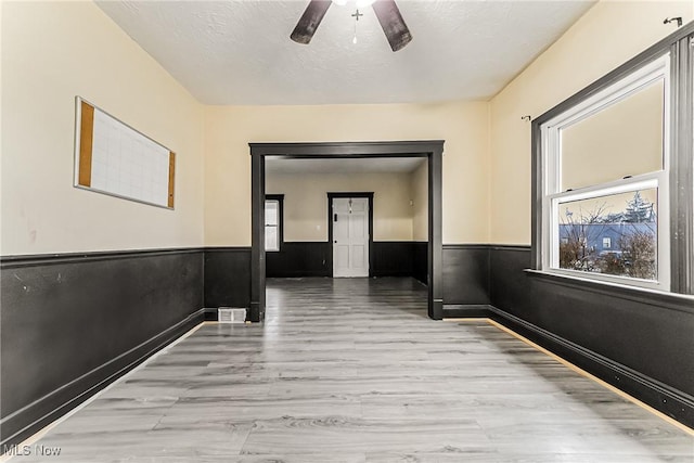 corridor featuring a textured ceiling and light hardwood / wood-style flooring