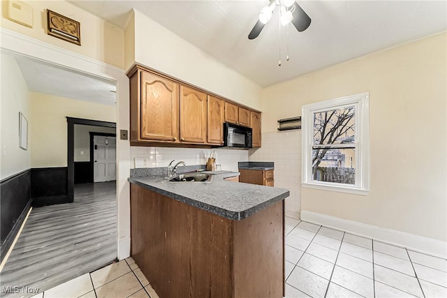 kitchen featuring ceiling fan, kitchen peninsula, sink, and light tile patterned floors