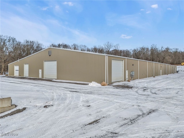 snow covered structure featuring a garage