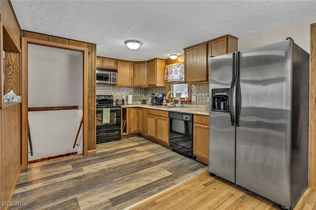 kitchen with sink, a textured ceiling, hardwood / wood-style flooring, decorative backsplash, and black appliances