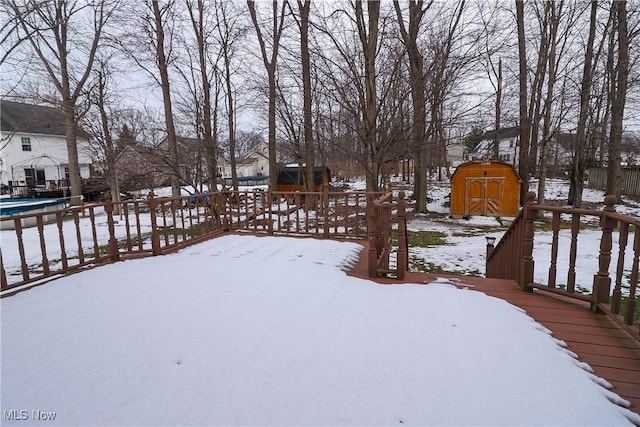 snowy yard featuring a deck and a storage shed