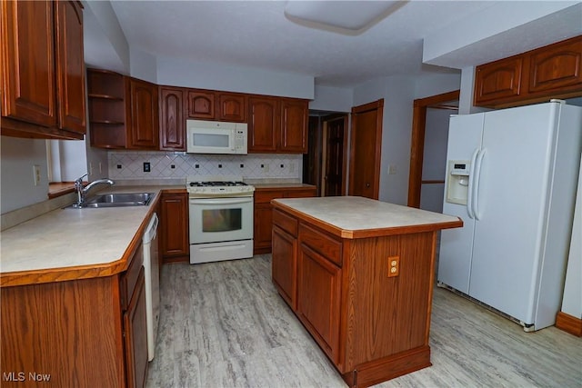 kitchen with a center island, sink, white appliances, and light hardwood / wood-style flooring