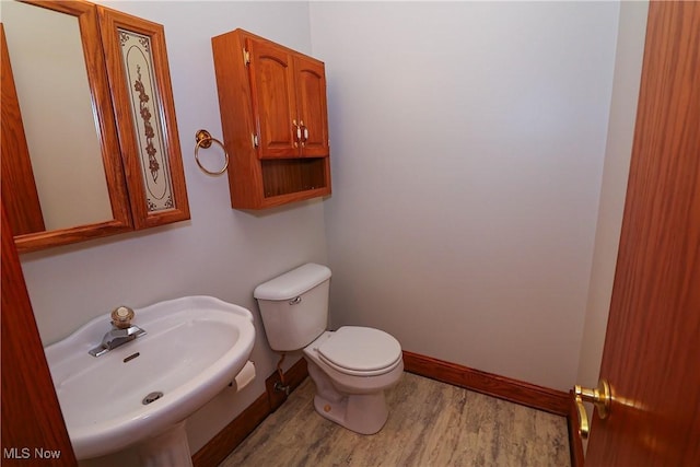 bathroom with toilet, sink, and hardwood / wood-style floors