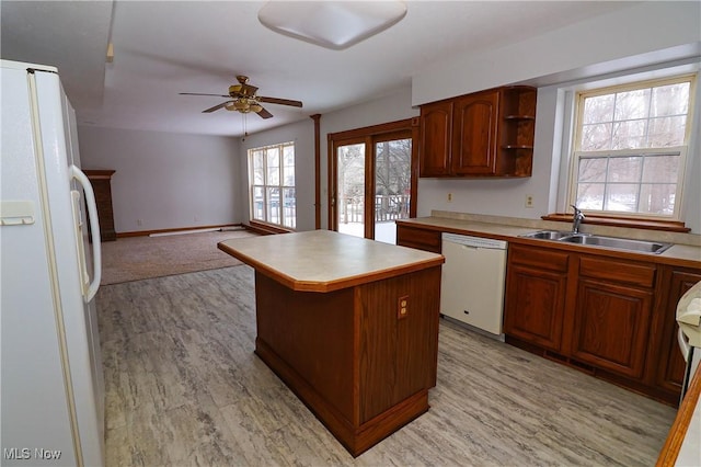 kitchen featuring a kitchen island, sink, light wood-type flooring, a brick fireplace, and white appliances