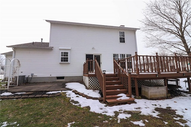 snow covered rear of property with a deck and a patio area