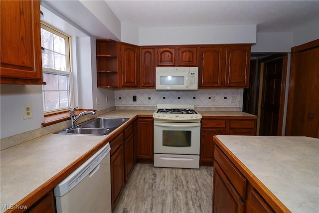 kitchen with tasteful backsplash, sink, white appliances, and light wood-type flooring