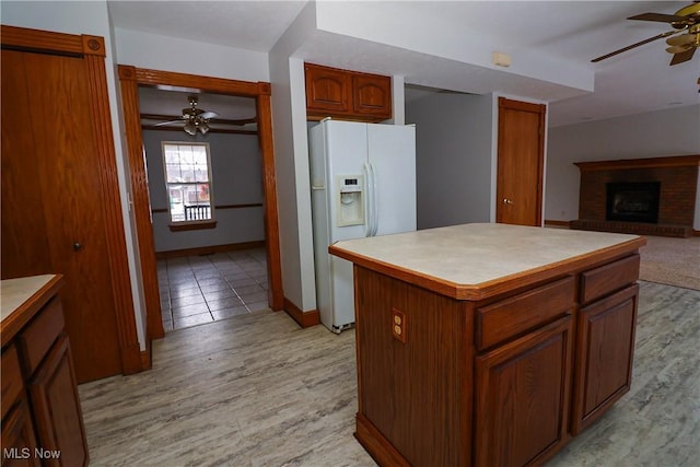 kitchen with ceiling fan, white refrigerator with ice dispenser, light hardwood / wood-style floors, and a kitchen island