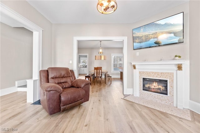 sitting room with a tile fireplace and light wood-type flooring