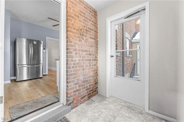 interior space with brick wall and ceiling fan