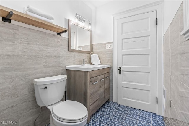 bathroom with tile walls, vanity, and toilet