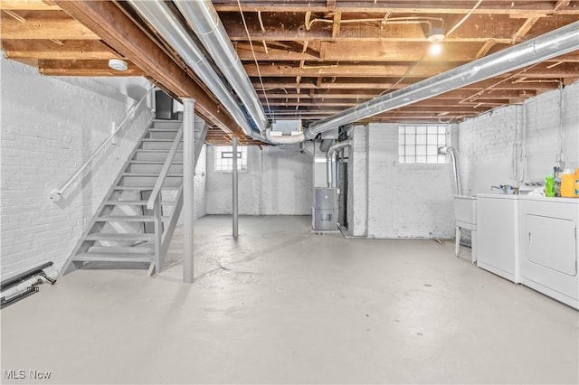 basement with water heater, a healthy amount of sunlight, and washing machine and clothes dryer