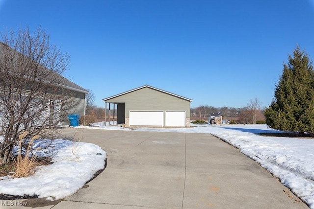 snow covered property featuring a garage and an outdoor structure