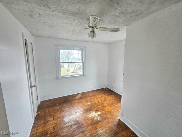 empty room featuring ceiling fan, dark hardwood / wood-style flooring, and a textured ceiling