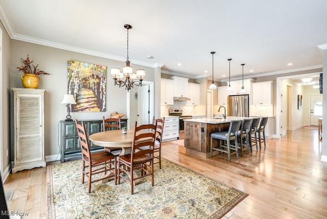 dining space with crown molding, a chandelier, sink, and light wood-type flooring