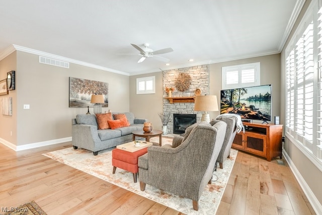 living room with a fireplace, light hardwood / wood-style flooring, ornamental molding, and ceiling fan