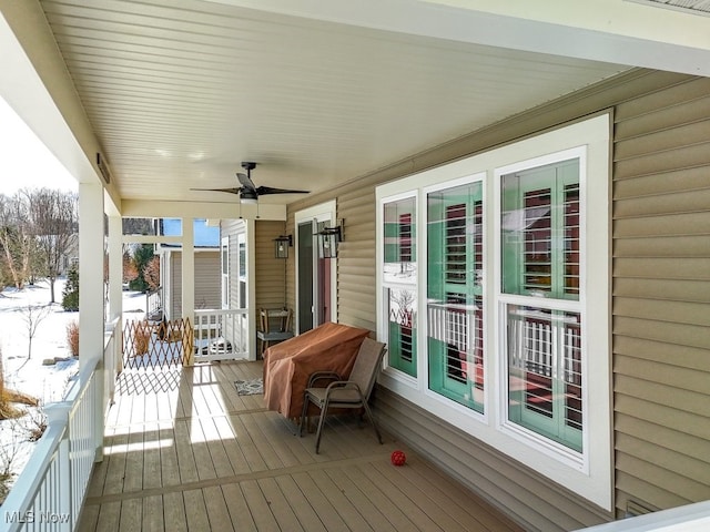 snow covered deck featuring ceiling fan and a porch