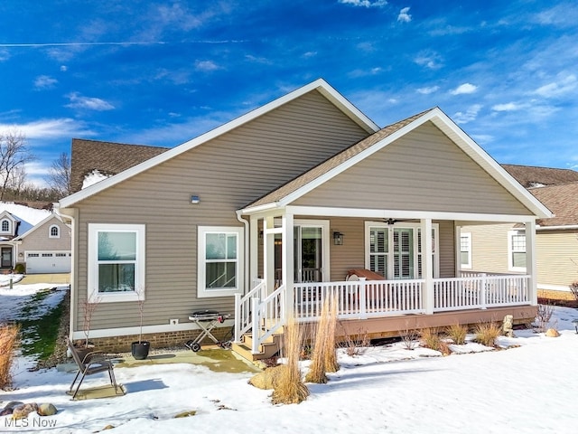 snow covered property with a garage and a porch