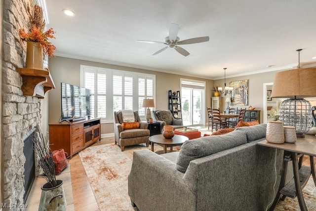 living room featuring crown molding, a healthy amount of sunlight, a stone fireplace, and light hardwood / wood-style floors