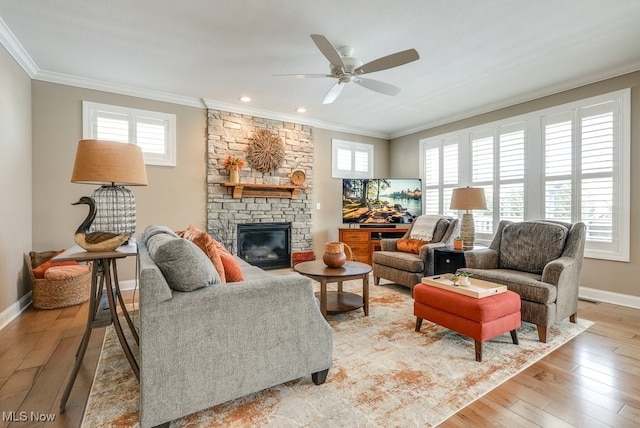 living room with a fireplace, ornamental molding, ceiling fan, and light wood-type flooring