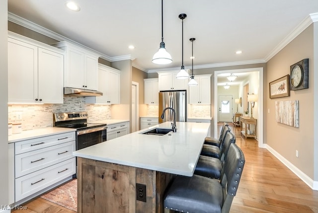 kitchen featuring an island with sink, stainless steel appliances, sink, and white cabinets