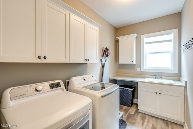 laundry area with cabinets, sink, washing machine and clothes dryer, and light wood-type flooring