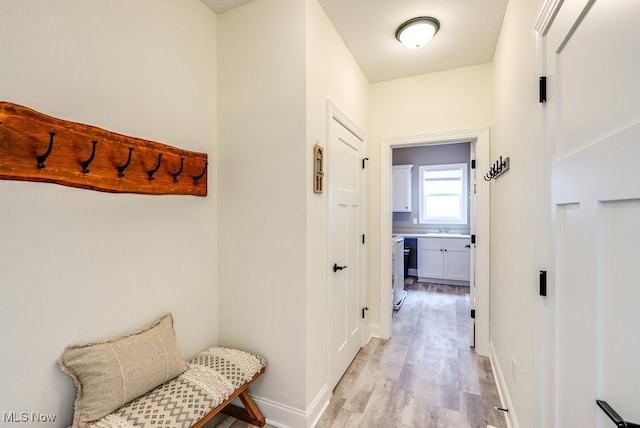 hallway with sink and light hardwood / wood-style flooring