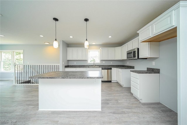 kitchen featuring white cabinetry, hanging light fixtures, stainless steel appliances, and a center island